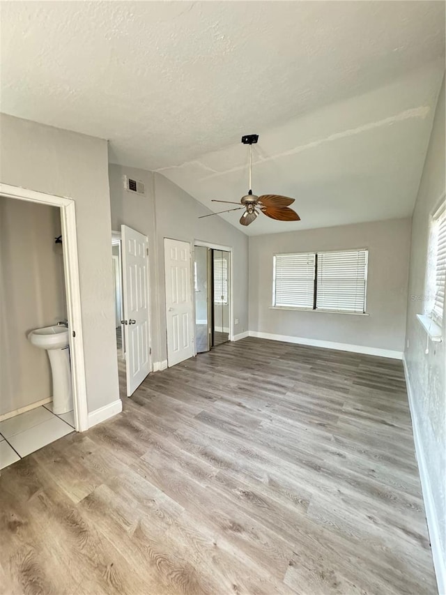 interior space featuring vaulted ceiling, light hardwood / wood-style flooring, a textured ceiling, and ceiling fan