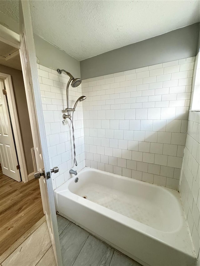 bathroom featuring tiled shower / bath, a textured ceiling, and hardwood / wood-style flooring