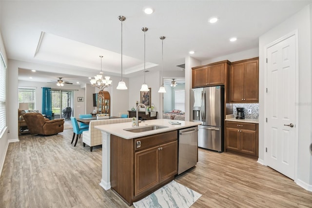 kitchen featuring light hardwood / wood-style floors, sink, a kitchen island with sink, appliances with stainless steel finishes, and decorative light fixtures