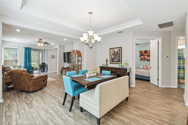 dining area featuring light hardwood / wood-style floors, ceiling fan with notable chandelier, a raised ceiling, and ornamental molding