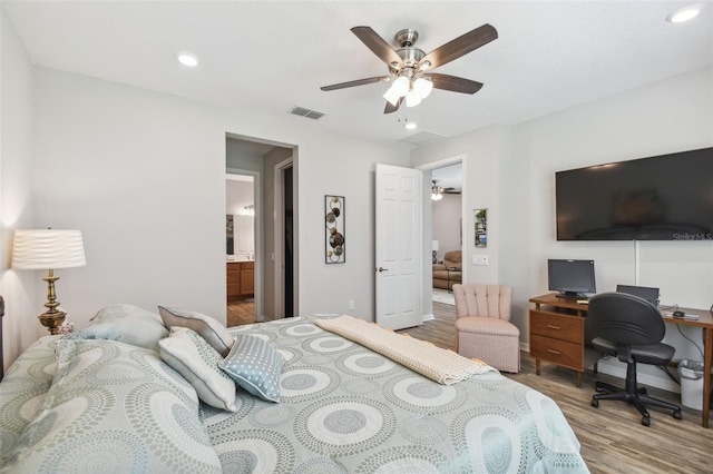 bedroom featuring ceiling fan, ensuite bath, and light wood-type flooring