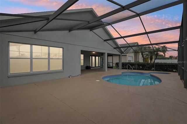 pool at dusk with a lanai and a patio