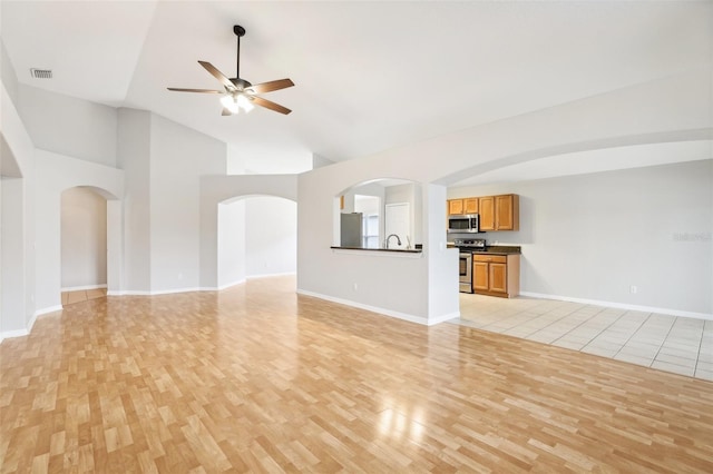 unfurnished living room with high vaulted ceiling, light hardwood / wood-style flooring, and ceiling fan