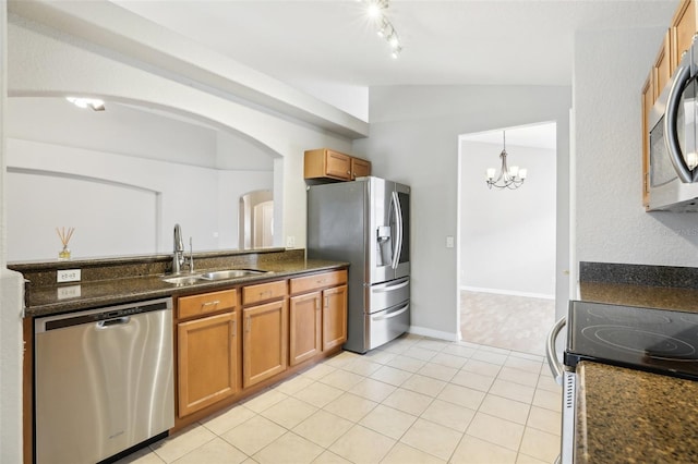 kitchen with sink, a chandelier, lofted ceiling, light tile patterned floors, and appliances with stainless steel finishes