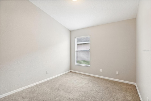 empty room featuring carpet and vaulted ceiling