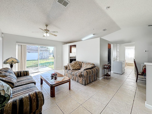 living room with a textured ceiling, ceiling fan, and light tile patterned floors