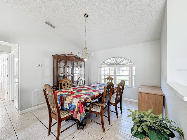 dining room featuring vaulted ceiling, a textured ceiling, and light tile patterned flooring