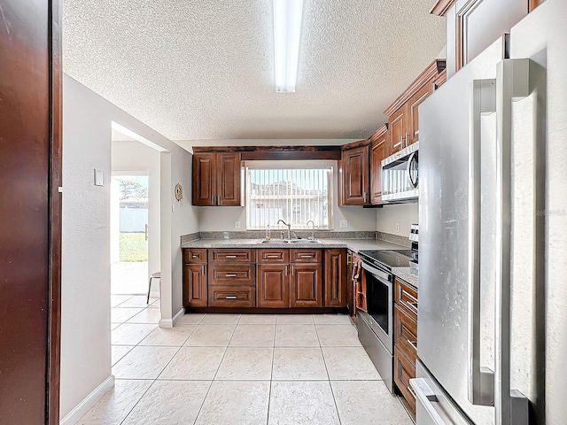 kitchen with stainless steel appliances, a textured ceiling, sink, and light tile patterned flooring