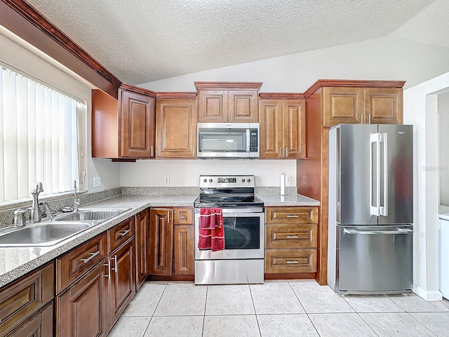 kitchen with a textured ceiling, vaulted ceiling, stainless steel appliances, and light tile patterned flooring