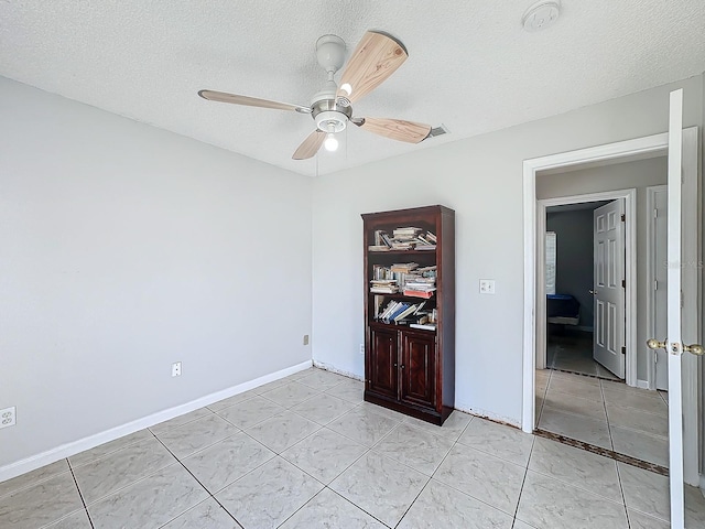 tiled spare room featuring a textured ceiling and ceiling fan