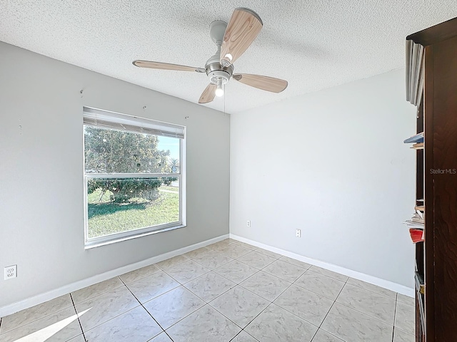 empty room featuring a textured ceiling, light tile patterned flooring, and ceiling fan