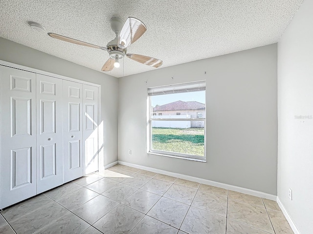 unfurnished bedroom with light tile patterned flooring, a textured ceiling, a closet, and ceiling fan