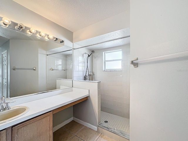 bathroom with vanity, a textured ceiling, a tile shower, and tile patterned floors