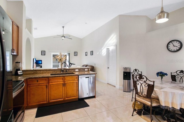 kitchen with hanging light fixtures, dark stone countertops, sink, light tile patterned floors, and appliances with stainless steel finishes