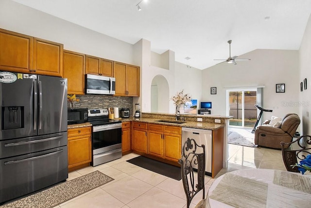 kitchen featuring kitchen peninsula, light tile patterned floors, appliances with stainless steel finishes, high vaulted ceiling, and sink