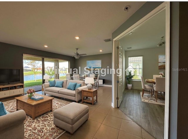 living room featuring ceiling fan, light wood-type flooring, and plenty of natural light