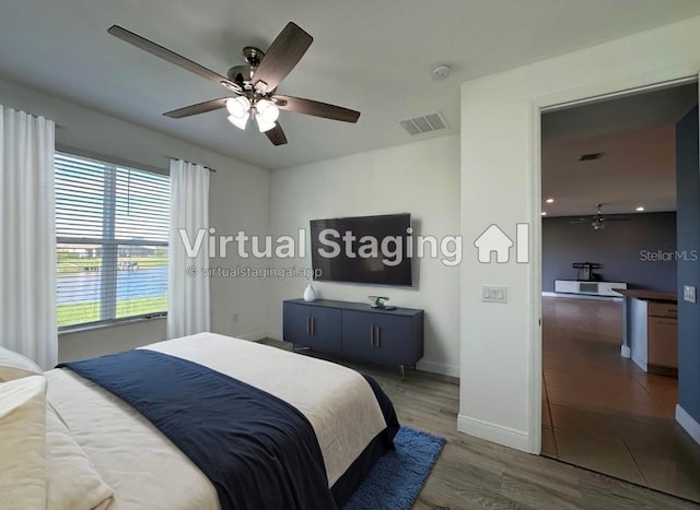 bedroom with dark hardwood / wood-style flooring, a water view, and ceiling fan