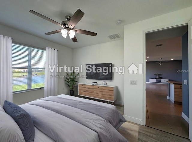 bedroom with a water view, ceiling fan, and tile patterned flooring