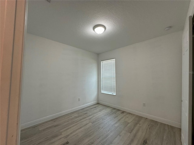 unfurnished room with a textured ceiling and light wood-type flooring