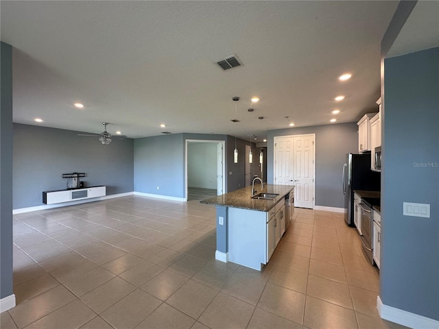 kitchen featuring white cabinets, a center island with sink, appliances with stainless steel finishes, light tile patterned flooring, and sink