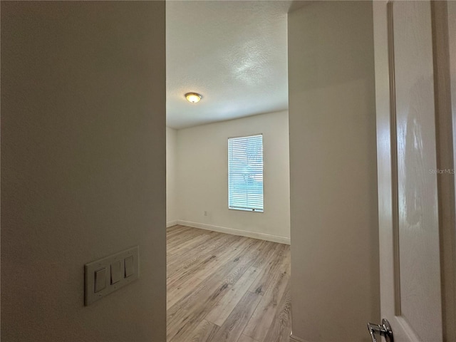 empty room with a textured ceiling and light wood-type flooring