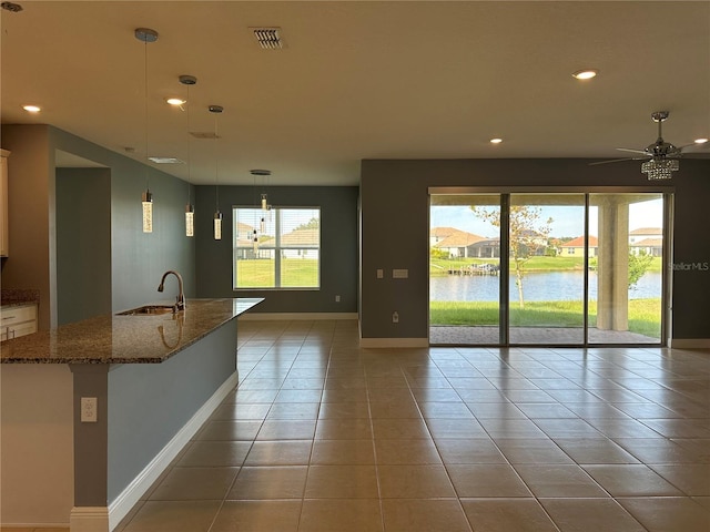 interior space with sink, light tile patterned flooring, a water view, and plenty of natural light