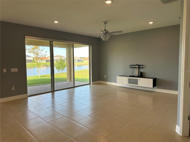 tiled spare room with a water view and ceiling fan