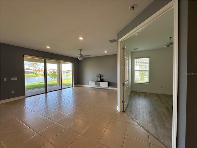 spare room featuring a water view, light hardwood / wood-style floors, and ceiling fan