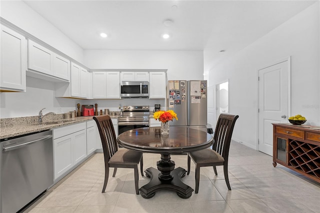 kitchen featuring light stone countertops, sink, stainless steel appliances, white cabinets, and light tile patterned floors