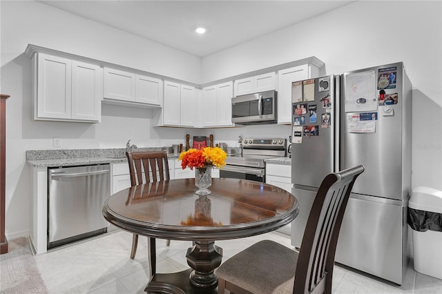 kitchen featuring white cabinetry, light stone countertops, appliances with stainless steel finishes, and light tile patterned floors