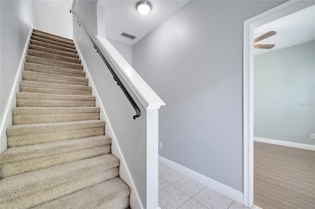 staircase with hardwood / wood-style floors and a textured ceiling