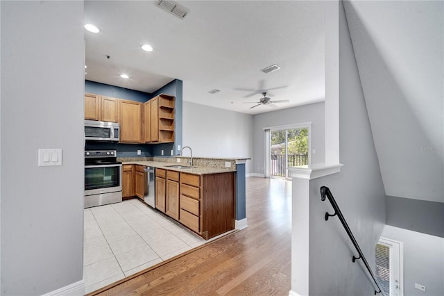 kitchen with kitchen peninsula, ceiling fan, appliances with stainless steel finishes, light wood-type flooring, and sink