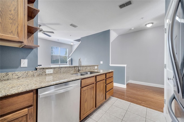 kitchen with sink, light hardwood / wood-style floors, stainless steel appliances, ceiling fan, and light stone counters