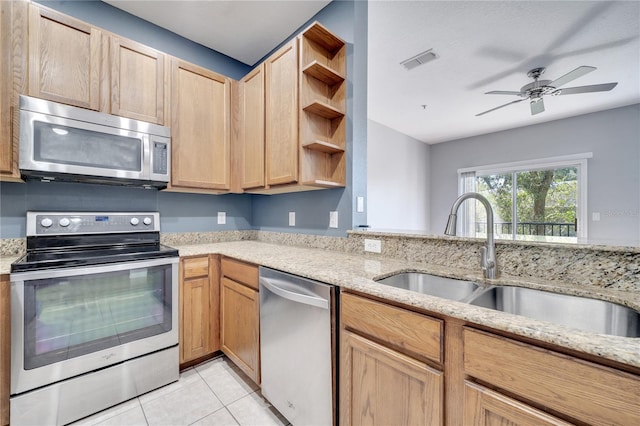 kitchen featuring light brown cabinetry, sink, stainless steel appliances, light stone counters, and light tile patterned floors