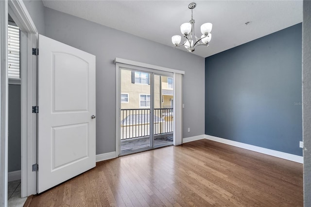 empty room featuring hardwood / wood-style flooring and a chandelier