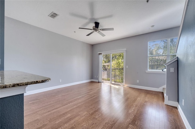 unfurnished living room with a textured ceiling, hardwood / wood-style flooring, and ceiling fan