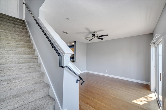 stairs featuring wood-type flooring and ceiling fan