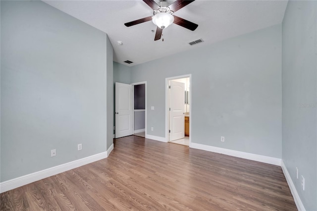 unfurnished bedroom featuring ensuite bathroom, hardwood / wood-style flooring, a textured ceiling, and ceiling fan