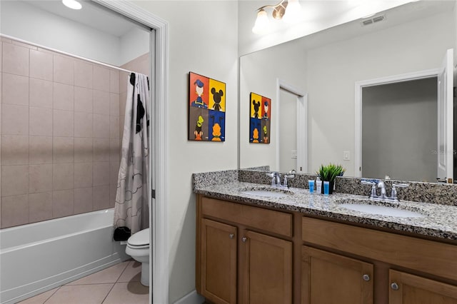 bathroom with a sink, toilet, double vanity, and tile patterned floors