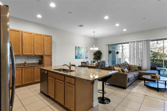 kitchen with a breakfast bar, brown cabinets, a notable chandelier, stainless steel appliances, and a sink