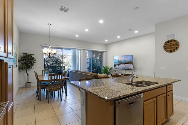 kitchen featuring visible vents, a center island with sink, a sink, stainless steel dishwasher, and light stone countertops