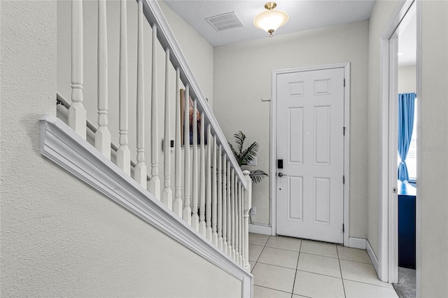 entryway featuring tile patterned floors, visible vents, stairway, and baseboards