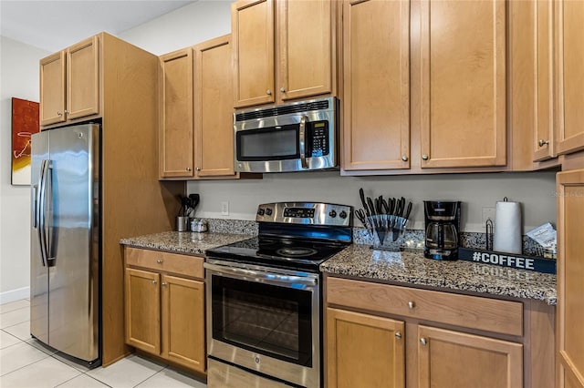 kitchen featuring light tile patterned flooring, stainless steel appliances, and dark stone counters