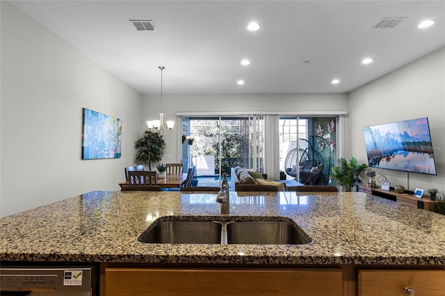 kitchen with visible vents, a sink, stone countertops, open floor plan, and dishwashing machine