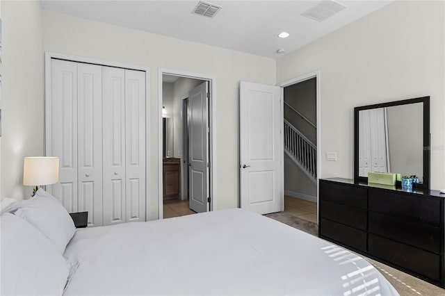 bedroom with tile patterned floors, visible vents, and a closet