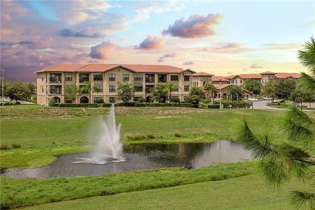 view of property's community with a water view and a lawn