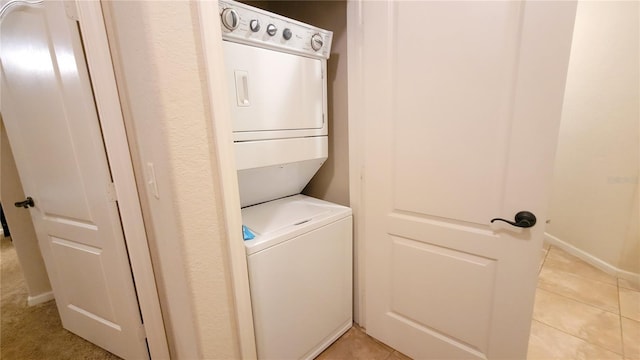 washroom featuring stacked washer / drying machine and light tile patterned floors