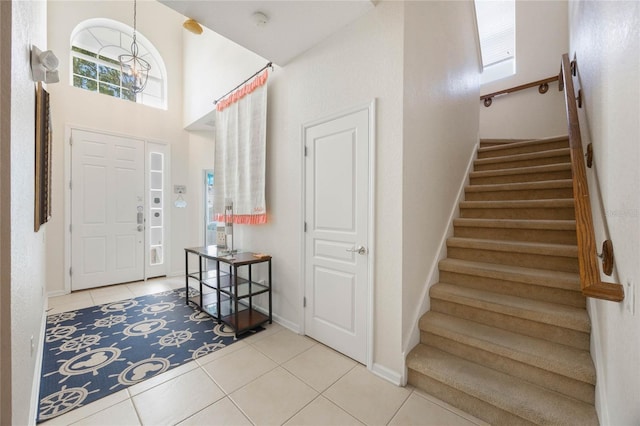 foyer featuring a towering ceiling, a healthy amount of sunlight, and light tile patterned floors