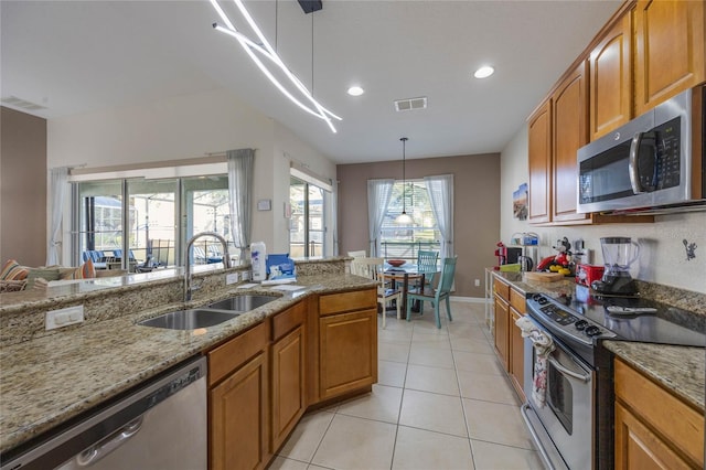 kitchen featuring light stone counters, stainless steel appliances, sink, and hanging light fixtures