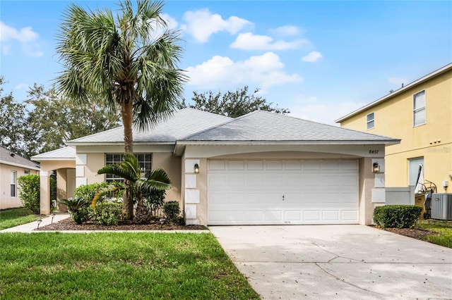 view of front facade with a front yard, central AC, and a garage